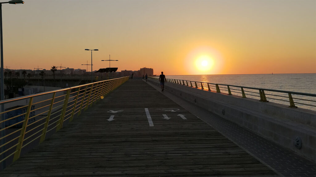 Person joggar på piren i soluppgången.