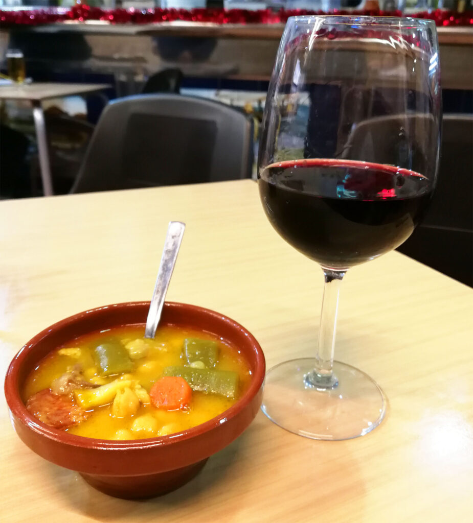 en skål med kikärtssoppa och ett glas rödvin